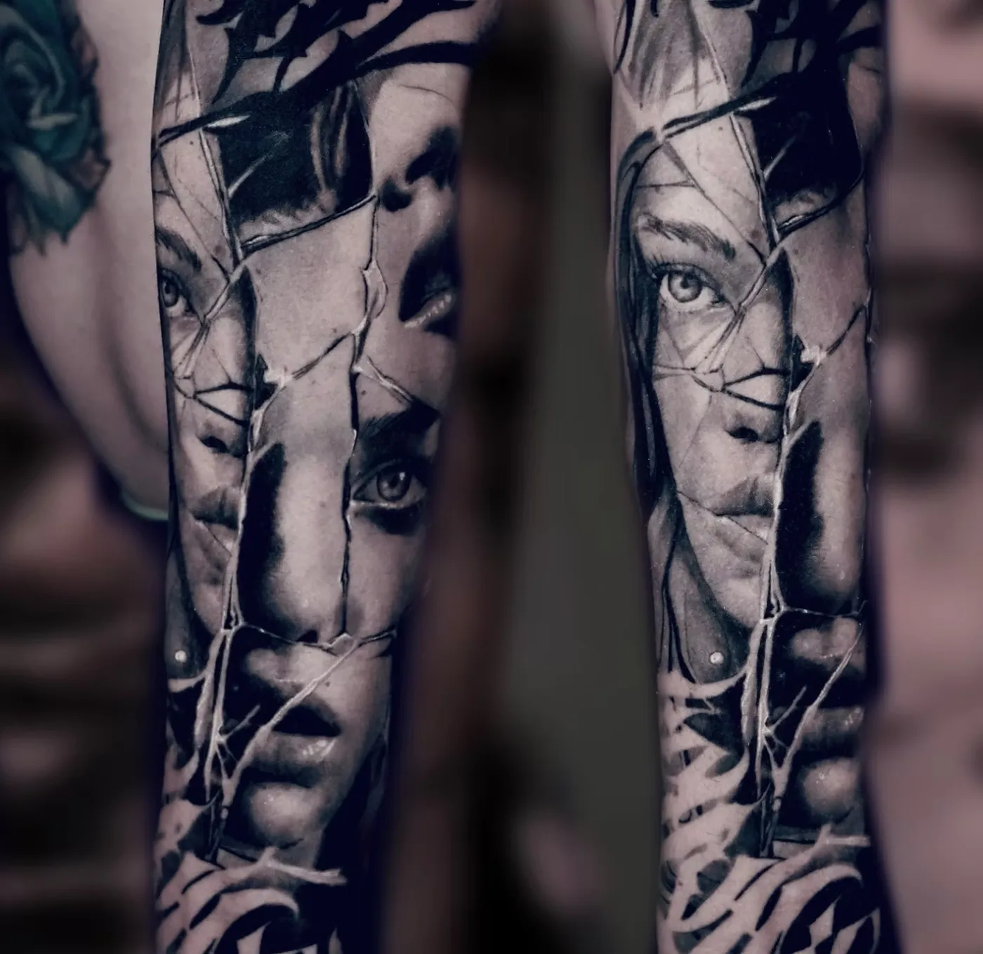 Two forearms with shattered-glass portraits and lettering